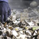 Technician handling a pile of discarded electronic components as part of e-waste removal services Kent WA.