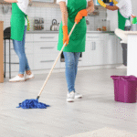 Professional cleaning crew mopping and organizing a modern kitchen space.