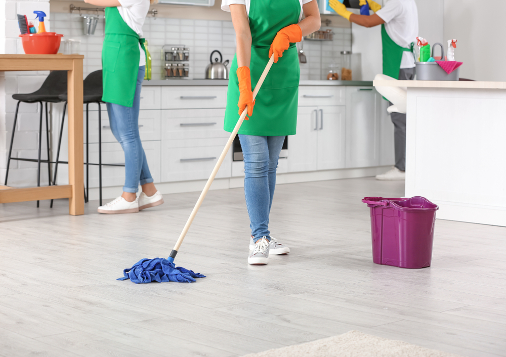 Professional cleaning crew mopping and organizing a modern kitchen space.